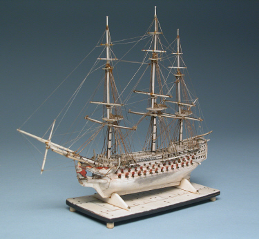   PRISONER-OF-WAR MINIATURE BONE MODEL OF A SHIP-OF-THE-LINE, circa 1800, four decker with 120 guns, carved and polychromed female figurehead and stern-castle; mounted on bone and ebony base. Height 7 ¼ in. Length 8 ¾ in.